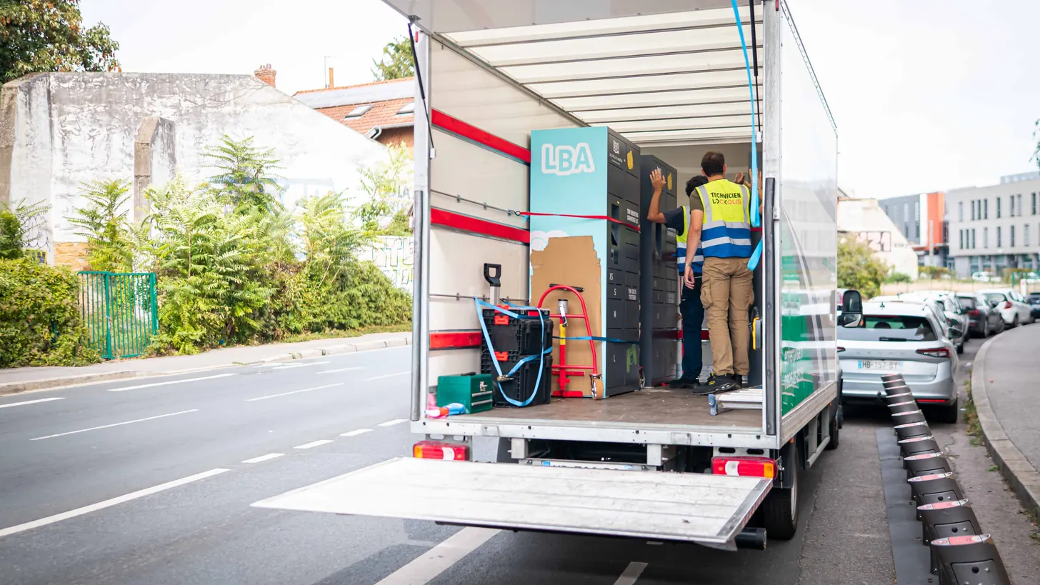 Camion à hayon ouvert, avec deux consignes sanglées à l’intérieur et un technicien Lockolis