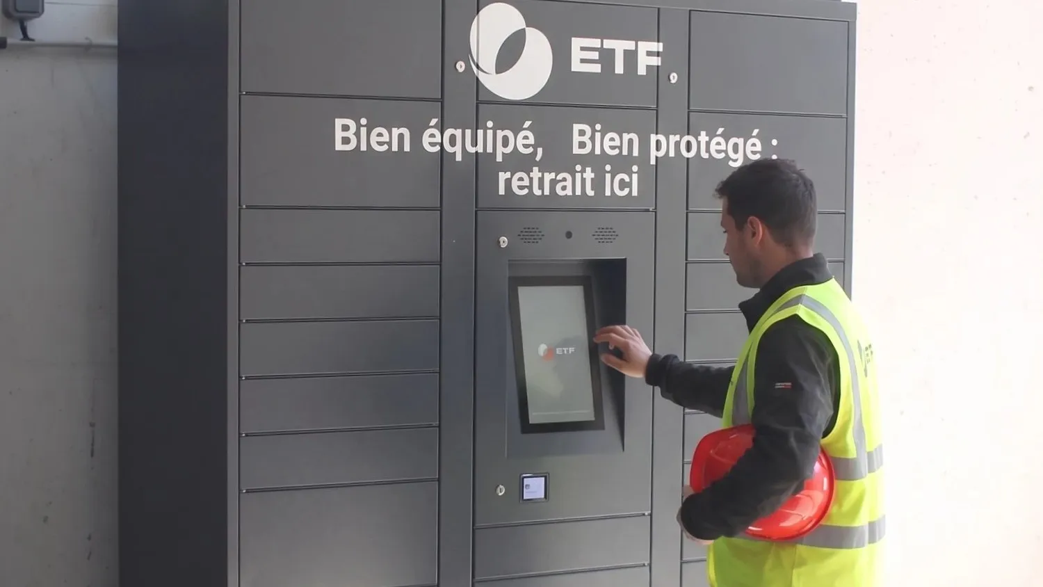 Ouvrier en gilet haute visibilité retirant ses EPI dans un casier connecté