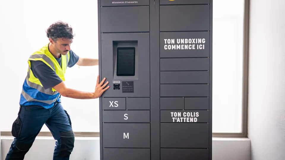 Un technicien Lockolis ajuste la position d’une consigne connectée dans un hall