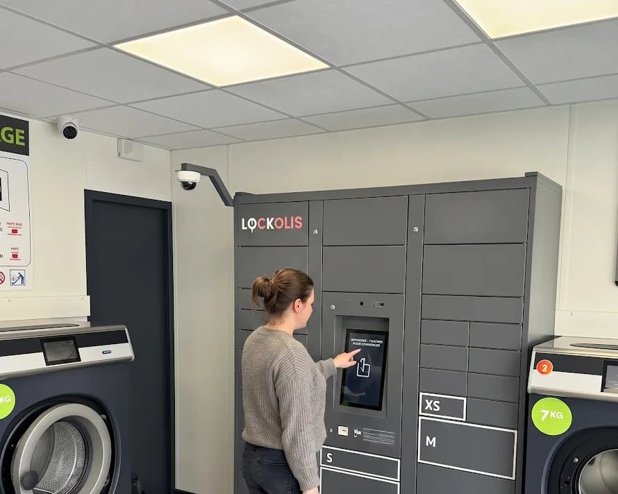 Cliente déposant son linge dans un locker Lockolis installé dans une laverie automatique